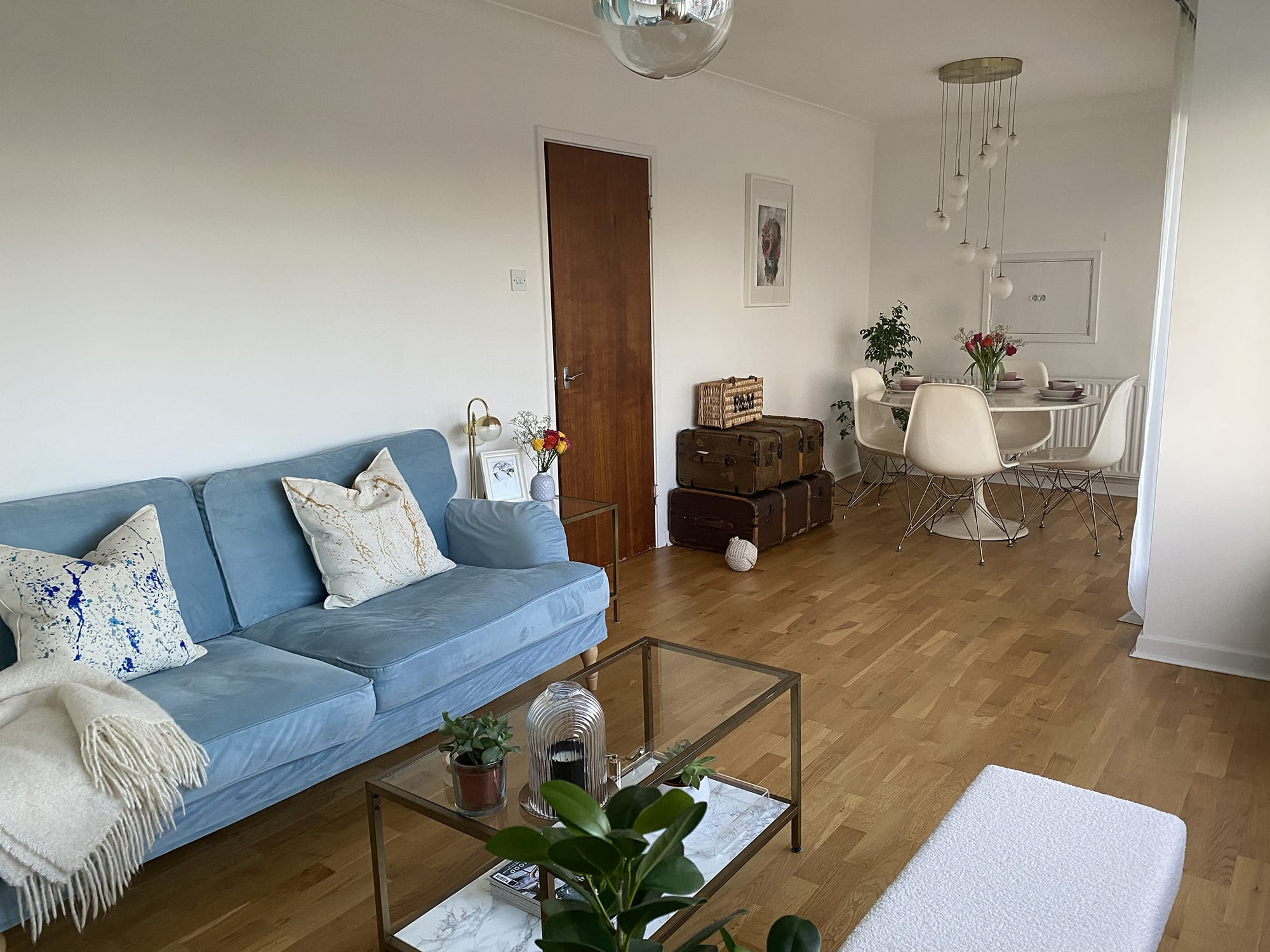 Blue sofa with white walls, round dining table and trunks