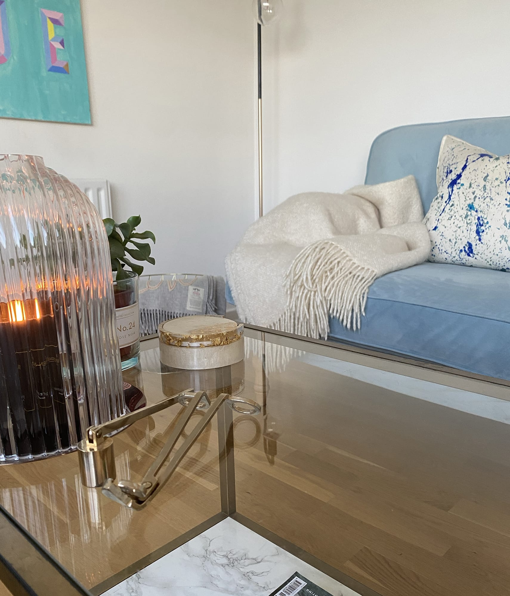 Coffee table with candle and blue sofa in the background