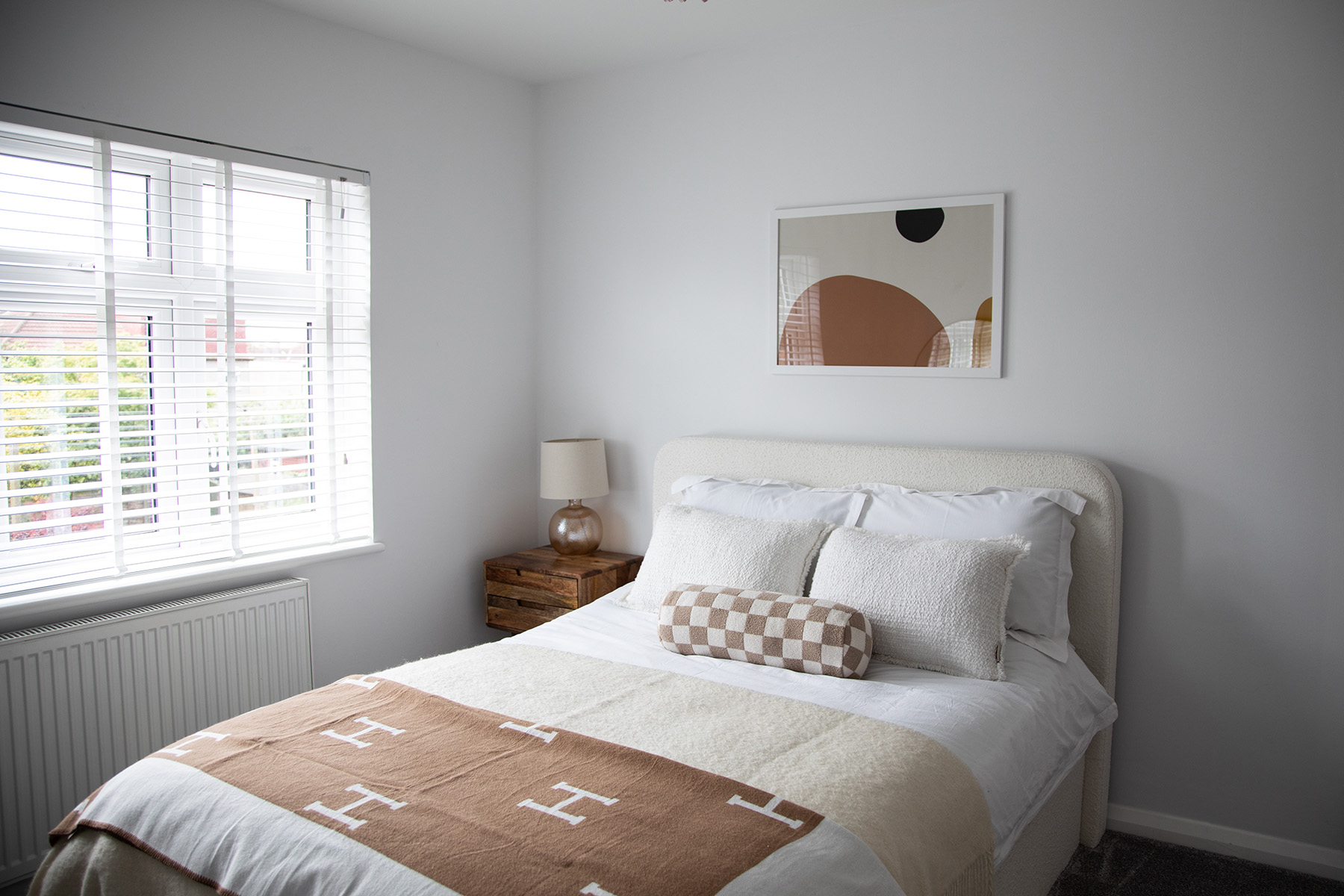 White bed in a white room with 6 butterfly photos on the wall